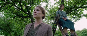 Movie still from “A Hidden Life” (2019), directed by Terrence Malick – A woman standing next to a man on a tree; Medium shot, Low angle