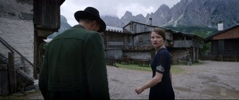 Movie still from “A Hidden Life” (2019), directed by Terrence Malick – A man and a woman standing in front of a building; Medium shot, Over the shoulder angle