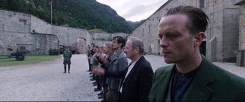 Movie still from “A Hidden Life” (2019), directed by Terrence Malick – A group of men standing next to each other in front of a building; Medium shot, Over the shoulder angle