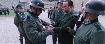 Movie still from “A Hidden Life” (2019), directed by Terrence Malick – A group of men in uniforms are holding hands; Medium shot, Over the shoulder angle