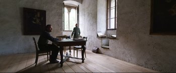 Movie still from “A Hidden Life” (2019), directed by Terrence Malick – Two men sitting at a table in a room; Wide shot, High angle