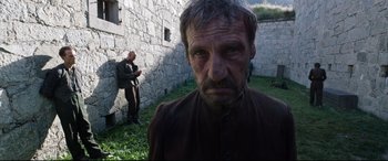 Movie still from “A Hidden Life” (2019), directed by Terrence Malick – A man in a brown shirt is looking into the camera; Medium shot, Low angle