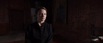 Movie still from “A Hidden Life” (2019), directed by Terrence Malick – A woman in a black jacket is in a room; Medium shot, Over the shoulder angle