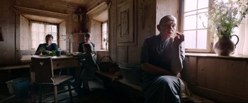 Movie still from “A Hidden Life” (2019), directed by Terrence Malick – An older man sitting in a room with a young girl; Medium shot, High angle