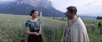 Movie still from “A Hidden Life” (2019), directed by Terrence Malick – Two people in a field with mountains in the background; Medium shot, Over the shoulder angle