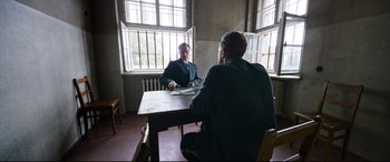 Movie still from “A Hidden Life” (2019), directed by Terrence Malick – Two men sitting at a table in front of each other; Wide shot, Over the shoulder angle