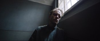 Movie still from “A Hidden Life” (2019), directed by Terrence Malick – A man standing next to a window in a dark room; Close Up shot, Low angle