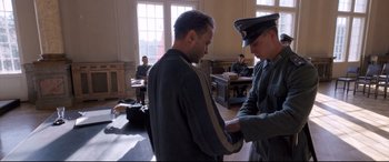 Movie still from “A Hidden Life” (2019), directed by Terrence Malick – Two men in uniforms are standing in a room; Medium shot, Over the shoulder angle
