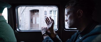 Movie still from “A Hidden Life” (2019), directed by Terrence Malick – A man with handcuffed hands looking out a window; Close Up shot, Low angle