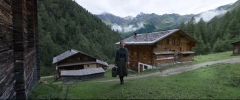 Movie still from “A Hidden Life” (2019), directed by Terrence Malick – A woman is walking on a hill near some houses; Wide shot, High angle