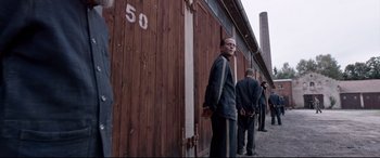Movie still from “A Hidden Life” (2019), directed by Terrence Malick – A group of men standing in front of a building; Wide shot, Low angle