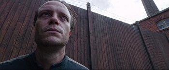 Movie still from “A Hidden Life” (2019), directed by Terrence Malick – A man standing in front of a wooden fence; Close Up shot, Low angle