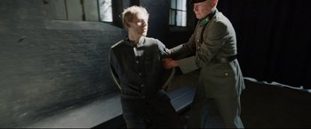 Movie still from “A Hidden Life” (2019), directed by Terrence Malick – A man in a military uniform is being held by another man; Medium shot, Over the shoulder angle