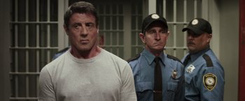 Movie still from “Escape Plan” (2013), directed by Mikael Håfström – A man and a police officer standing next to each other in front of a jail cell; Close Up shot, Over the shoulder angle