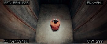 Movie still from “Escape Plan” (2013), directed by Mikael Håfström – An image of a person sitting in an orange chair; Extreme Wide shot, Overhead angle