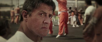 Movie still from “Escape Plan” (2013), directed by Mikael Håfström – A person wearing a prison uniform; Close Up shot, Over the shoulder angle
