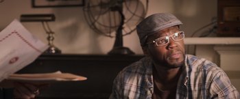 Movie still from “Escape Plan” (2013), directed by Mikael Håfström – A man wearing glasses sitting in front of a fan; Close Up shot, Over the shoulder angle