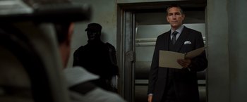Movie still from “Escape Plan” (2013), directed by Mikael Håfström – A man in a suit and tie standing next to another man in a suit and tie; Medium shot, Over the shoulder angle