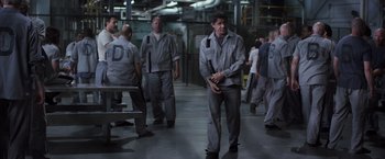Movie still from “Escape Plan” (2013), directed by Mikael Håfström – A group of men in grey suits walking in a warehouse; Wide shot, Over the shoulder angle
