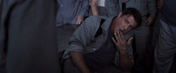 Movie still from “Escape Plan” (2013), directed by Mikael Håfström – A man with his head in his hands; Medium shot, Low angle