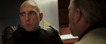 Movie still from “Escape Plan” (2013), directed by Mikael Håfström – A man wearing a leather jacket is talking to another man; Close Up shot, Over the shoulder angle
