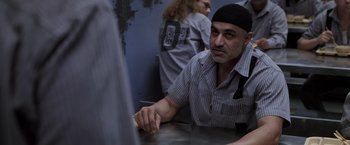 Movie still from “Escape Plan” (2013), directed by Mikael Håfström – A man sitting at a table in front of another man; Medium shot, Over the shoulder angle