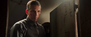 Movie still from “Escape Plan” (2013), directed by Mikael Håfström – A person wearing a suit and tie; Close Up shot, Over the shoulder angle