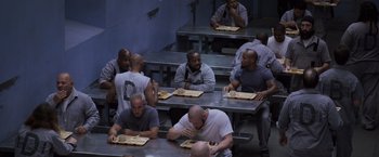 Movie still from “Escape Plan” (2013), directed by Mikael Håfström – A group of men sitting at tables eating food; Wide shot, High angle