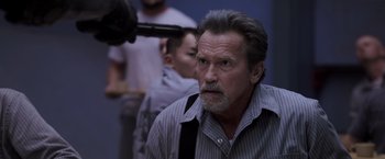 Movie still from “Escape Plan” (2013), directed by Mikael Håfström – An older man with gray hair and a beard; Close Up shot, Over the shoulder angle