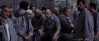 Movie still from “Escape Plan” (2013), directed by Mikael Håfström – A group of men sitting next to each other in a room; Medium shot, High angle