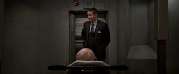 Movie still from “Escape Plan” (2013), directed by Mikael Håfström – A man in a suit standing in front of an elevator; Medium shot, Low angle