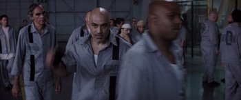 Movie still from “Escape Plan” (2013), directed by Mikael Håfström – A group of men standing next to each other in a room; Medium shot, Over the shoulder angle