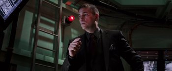 Movie still from “Escape Plan” (2013), directed by Mikael Håfström – A man wearing a suit and tie holding a cigarette; Medium shot, Low angle