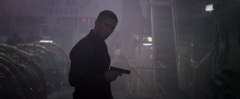 Movie still from “Escape Plan” (2013), directed by Mikael Håfström – A man holding a gun while standing in a dark room; Medium shot, Low angle