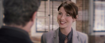 Movie still from “Escape Plan” (2013), directed by Mikael Håfström – A woman wearing a suit and tie smiling at a man; Close Up shot, Over the shoulder angle