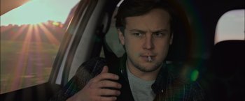 Movie still from “Escape Room: Tournament of Champions” (2021), directed by Adam Robitel – A man sitting in the drivers seat of a car smoking a cigarette; Close Up shot, Over the shoulder angle