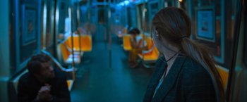 Movie still from “Escape Room: Tournament of Champions” (2021), directed by Adam Robitel – A woman wearing headphones sitting on a subway train; Medium shot, Over the shoulder angle