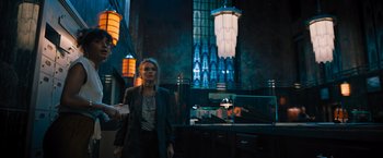 Movie still from “Escape Room: Tournament of Champions” (2021), directed by Adam Robitel – A woman standing in front of a building holding a card; Wide shot, Low angle