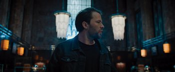 Movie still from “Escape Room: Tournament of Champions” (2021), directed by Adam Robitel – A man in a black jacket standing in front of a window; Medium shot, Low angle