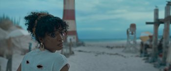 Movie still from “Escape Room: Tournament of Champions” (2021), directed by Adam Robitel – A man standing on a beach next to a light house; Close Up shot, Over the shoulder angle