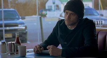 Movie still from “Eternal Sunshine of the Spotless Mind” (2004), directed by Michel Gondry – A man sitting at a table with a pen in his hand; Close Up shot, Over the shoulder angle