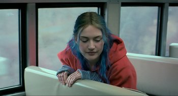Movie still from “Eternal Sunshine of the Spotless Mind” (2004), directed by Michel Gondry – A woman with blue hair sitting on a train; Close Up shot, Over the shoulder angle
