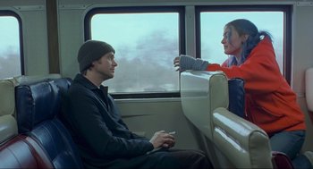 Movie still from “Eternal Sunshine of the Spotless Mind” (2004), directed by Michel Gondry – A man and a woman sitting on a train looking at each other; Medium shot, Over the shoulder angle