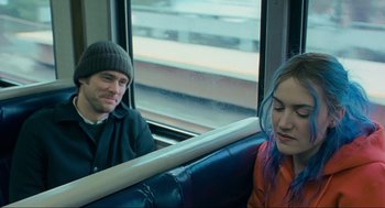 Movie still from “Eternal Sunshine of the Spotless Mind” (2004), directed by Michel Gondry – A man and a woman sitting on a train; Medium shot, Over the shoulder angle