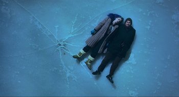 Movie still from “Eternal Sunshine of the Spotless Mind” (2004), directed by Michel Gondry – A man and a woman laying on the ground in the snow; Wide shot, Overhead angle