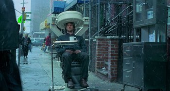 Movie still from “Eternal Sunshine of the Spotless Mind” (2004), directed by Michel Gondry – A man sitting on a chair with a tray on his head; Medium shot, Over the shoulder angle