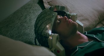 Movie still from “Eternal Sunshine of the Spotless Mind” (2004), directed by Michel Gondry – A man wearing a helmet and a pair of headphones on his head; Close Up shot, Overhead angle