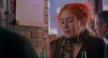 Movie still from “Eternal Sunshine of the Spotless Mind” (2004), directed by Michel Gondry – A woman sitting at a table eating a piece of pizza; Close Up shot, Over the shoulder angle