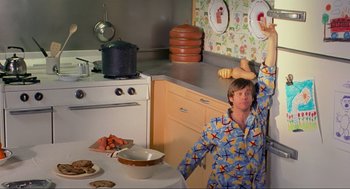 Movie still from “Eternal Sunshine of the Spotless Mind” (2004), directed by Michel Gondry – A person in a kitchen with a plate of food on the wall; Medium shot, Low angle
