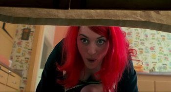 Movie still from “Eternal Sunshine of the Spotless Mind” (2004), directed by Michel Gondry – A woman with red hair is peeking out from under a table; Medium shot, Overhead angle